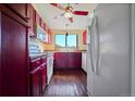 Galley kitchen with dark red cabinets and hardwood floors at 3656 S Depew St # 303, Denver, CO 80235