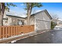 Exterior view of the attached garage with wooden fence and snowy surroundings at 2951 S Walden Ct, Aurora, CO 80013