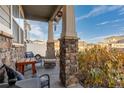 Covered porch with seating area, brick columns, and fall foliage at 3924 Alamosa Ct, Brighton, CO 80601