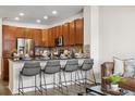 Modern kitchen with wood cabinetry, stainless steel appliances, and bar seating at 6760 Fern Dr, Denver, CO 80221