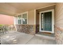 Covered front porch with stone accents and a dark green door at 15453 E 109Th Ave, Commerce City, CO 80022