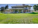 Back exterior showcasing a large home with a lush green lawn at 10690 County Road 1, Longmont, CO 80504