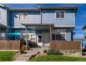 Townhouse with light blue exterior, front porch, and fenced yard at 12022 Locust St, Brighton, CO 80602