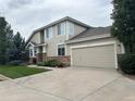 Two-story home with tan siding, stone accents, and a two-car garage at 7482 W Saratoga Pl, Littleton, CO 80123