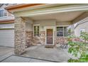 Covered porch with stone pillars and a small sitting area at 11729 Elkhart St, Commerce City, CO 80603