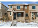 Modern two-story townhome with a covered porch and snowy landscape at 8683 Snake River St, Littleton, CO 80125