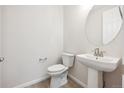 Modern powder room with pedestal sink and circular mirror at 1161 Colony Dr, Erie, CO 80026