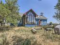 Unique blue farmhouse with a large sunroom and a deck, set against a natural backdrop at 11230 County Road 20, Fort Lupton, CO 80621