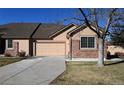 Tan two-story home with a two-car garage and landscaped yard at 6475 Orion Way, Arvada, CO 80007