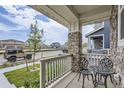 Relaxing front porch with stone columns, white railing, and small bistro set at 6233 N Liverpool St, Aurora, CO 80019