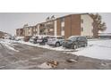 Apartment building exterior and parking lot in winter with snow on the ground at 300 Ash St # 208, Bennett, CO 80102