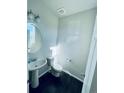 Clean powder room with pedestal sink, toilet, and dark wood flooring at 19085 E 66Th Ave, Denver, CO 80249