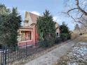 Side view of a two-story home with brick and scalloped siding, a front porch, and a metal fence at 2357 Grove St, Denver, CO 80211