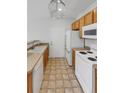 Bright kitchen with wood cabinets, white appliances, and a convenient pass-through at 22975 E Ontario Dr # 101, Aurora, CO 80016