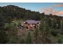 Backyard view of home showcasing large deck and mountain views at sunset at 22759 Mountain Spirit Way, Indian Hills, CO 80454