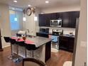 Modern kitchen with dark cabinets, granite countertops, and a breakfast bar at 15600 Bolling Dr, Denver, CO 80239