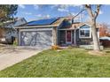 Two-story home with solar panels, gray garage door, red entry door, and a porch swing at 12195 Grape St, Thornton, CO 80241