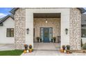 Inviting front porch with a blue door, stone accents, and charming planters at 17161 Jackson Ranch Ct, Monument, CO 80132