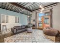 Spacious living room with exposed beams, concrete floors, and balcony access at 910 Santa Fe Dr # 19, Denver, CO 80204