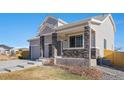 Two-story house with gray siding, stone accents, and a two-car garage at 7262 Xenophon Ct, Arvada, CO 80005