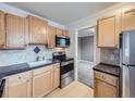 Kitchen with wood cabinets, stainless steel appliances and view into living area at 1 S Pennsylvania St # 102, Denver, CO 80209