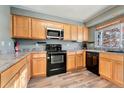 Kitchen with oak cabinets, black appliances, and laminate flooring at 19903 E 49Th Ave, Denver, CO 80249