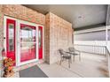 Covered porch with red door and brick entryway at 9042 Eldorado Ave, Longmont, CO 80504