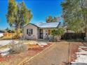 Tan house with dark shutters, small front porch, and snowy yard at 1794 Verbena St, Denver, CO 80220