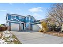 Two-story house with a blue exterior, brick accents, and a three-car garage at 12956 E 107Th Pl, Commerce City, CO 80022