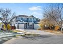 Two-story house with a blue exterior, brick accents, and a three-car garage at 12956 E 107Th Pl, Commerce City, CO 80022