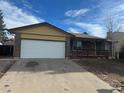 Brick Ranch home with a white garage door and small deck at 2084 S Rifle St, Aurora, CO 80013