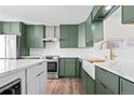 Stylish kitchen featuring green cabinets, marble countertops and a farmhouse sink at 13750 W 65Th Ave, Arvada, CO 80004
