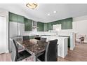 Modern kitchen with green cabinets, white countertops, and a kitchen island at 13750 W 65Th Ave, Arvada, CO 80004