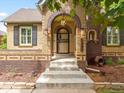 Brick home with arched entryway, landscaped yard, and steps leading to the entrance at 1345 Elm St, Denver, CO 80220