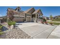 Two-car garage with a stone and siding exterior, and well-maintained landscaping at 8741 S Ukraine Ct, Aurora, CO 80016