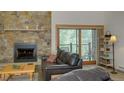 Cozy living room features a stone fireplace, leather sofa, and access to a balcony at 465 Four Oclock Rd # 323, Breckenridge, CO 80424