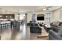 Open living room with dark gray couches, dark wood floors and a kitchen view at 9091 E 59Th North Pl, Denver, CO 80238