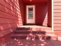 Front entrance with steps leading to the entrance and red siding at 7958 Downing St, Denver, CO 80229