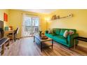 Living room with green couch, wood floors, and access to a balcony at 7525 W 62Nd Ave # 11, Arvada, CO 80003