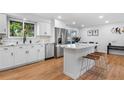 Modern white kitchen with island, stainless steel appliances, and hardwood floors at 8469 E Briarwood Ave, Centennial, CO 80112