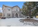 Two-story house with stone accents and a three-car garage; snow-covered yard at 6236 Oxford Peak Ln, Castle Rock, CO 80108