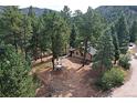 House surrounded by trees, driveway, and distant mountain views at 5673 Santa Clara Rd, Indian Hills, CO 80454