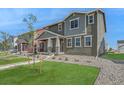 Two-story home with gray siding, white trim, and stone accents at 2990 Oxley St, Strasburg, CO 80136