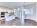 Bright kitchen with white cabinets, an island, and hardwood floors at 6435 E Cedar Ave, Denver, CO 80224