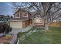 Two-story house with attached garage, landscaping, and large tree at dusk at 926 Highland Park Dr, Broomfield, CO 80020