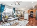 Open living room with hardwood floors, L-shaped sofa, and adjacent kitchen at 13042 Grant E Cir # C, Thornton, CO 80241