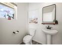 Modern powder room with pedestal sink, toilet, and wood-look floors at 10315 Rifle Ct, Commerce City, CO 80022