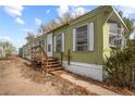 Exterior view of the mobile home, showcasing its green siding and surrounding area at 1219 Lilac Dr, Lochbuie, CO 80603