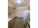 Kitchen with light wood cabinets, white appliances, and laminate flooring at 8031 Wolff St # H, Westminster, CO 80031