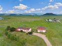 Aerial view showcasing a house, detached garage, and vast green landscape at 12155 Mesa View Rd, Larkspur, CO 80118